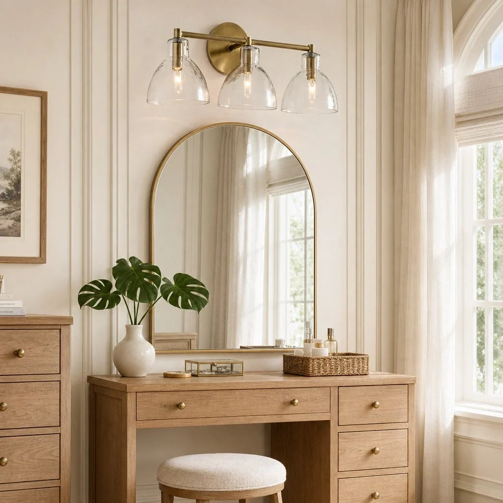 Brass 3-light hammered glass vanity light above an arched mirror and oak dressing table