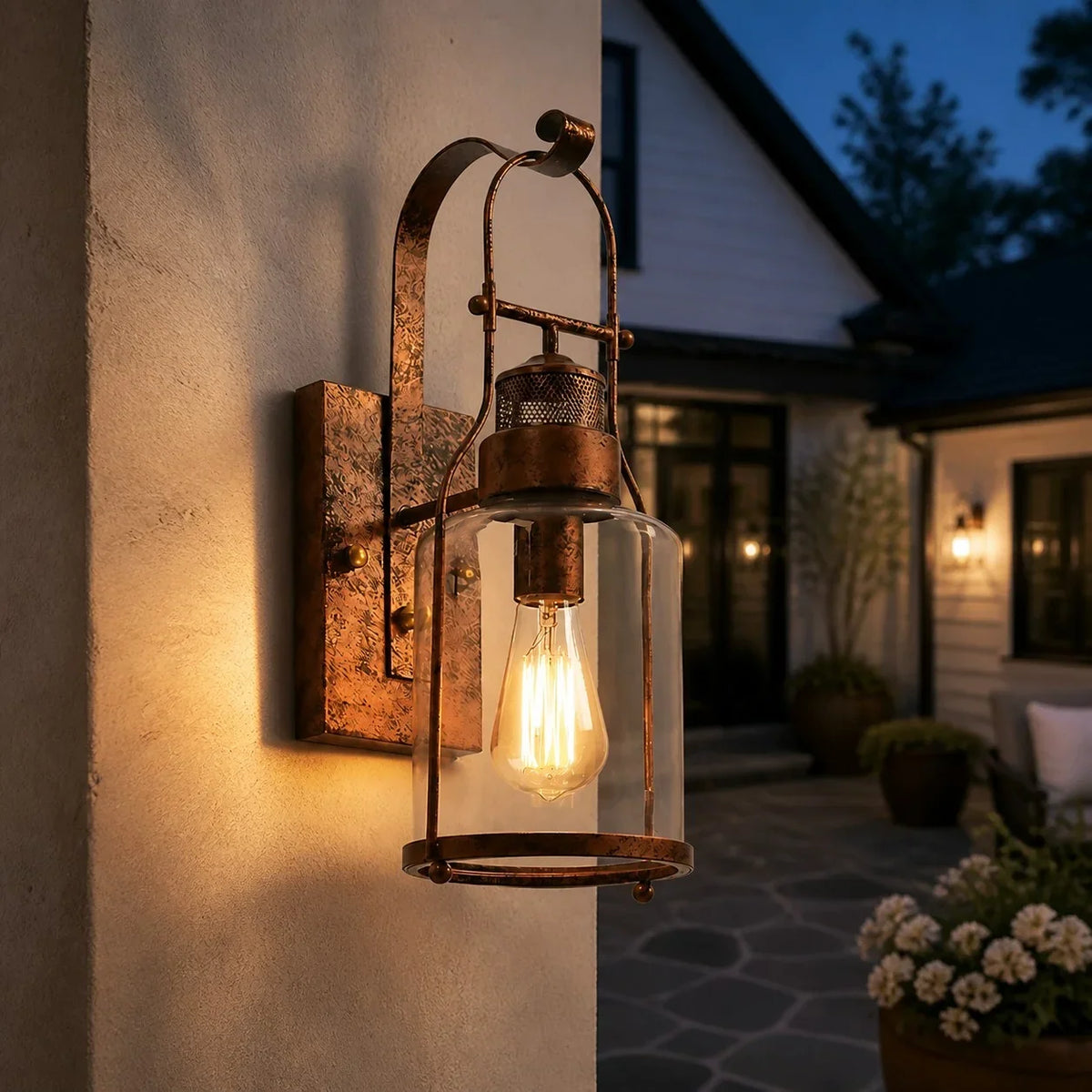 Rust lantern wall sconce glowing beside a courtyard entry at twilight
