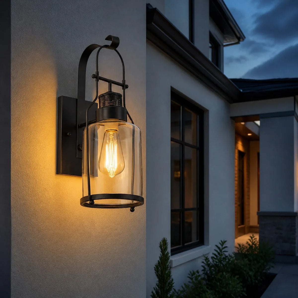 Black lantern wall sconce lighting a modern home exterior at dusk