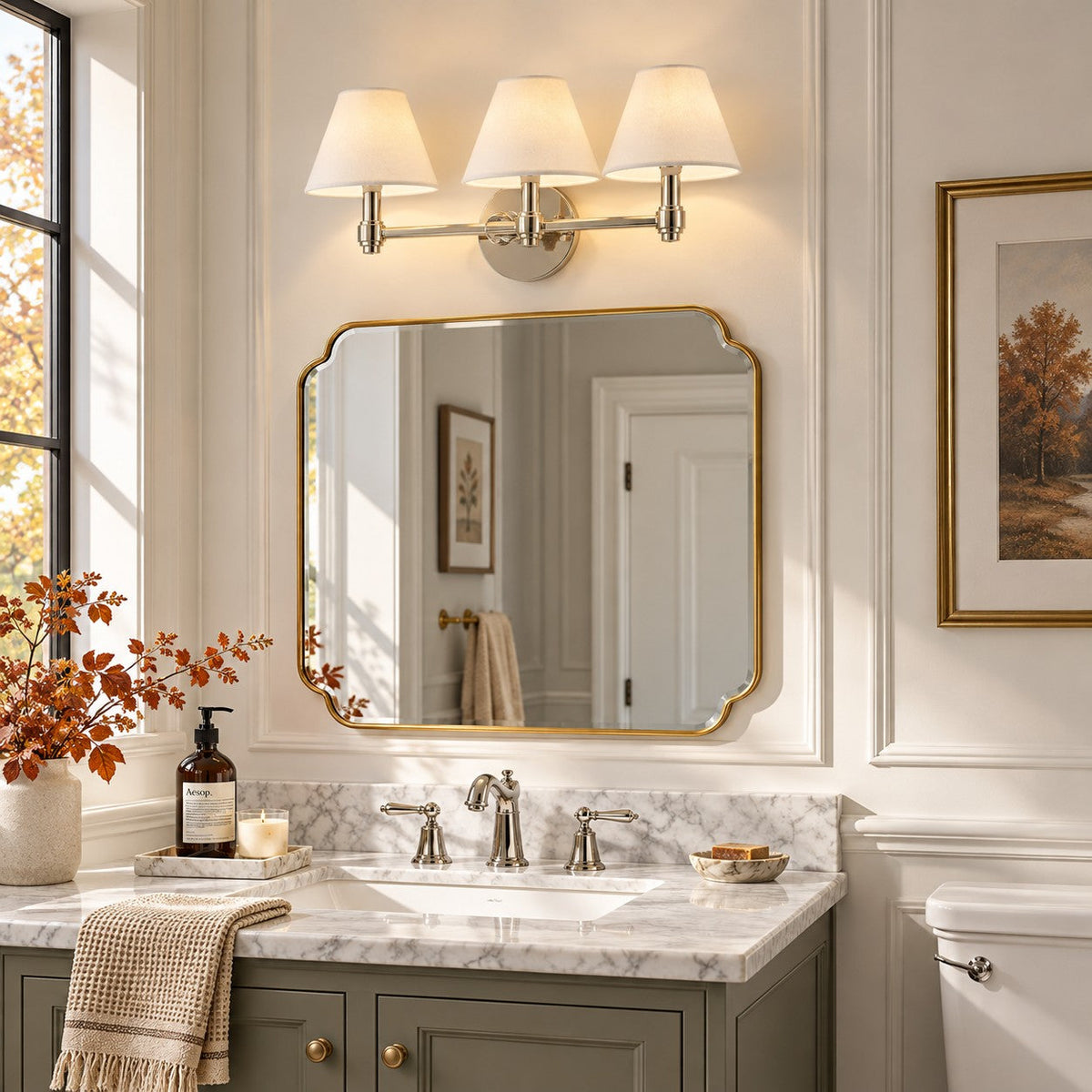 Terzetto polished nickel vanity sconce with linen shades above a vanity mirror and marble basin