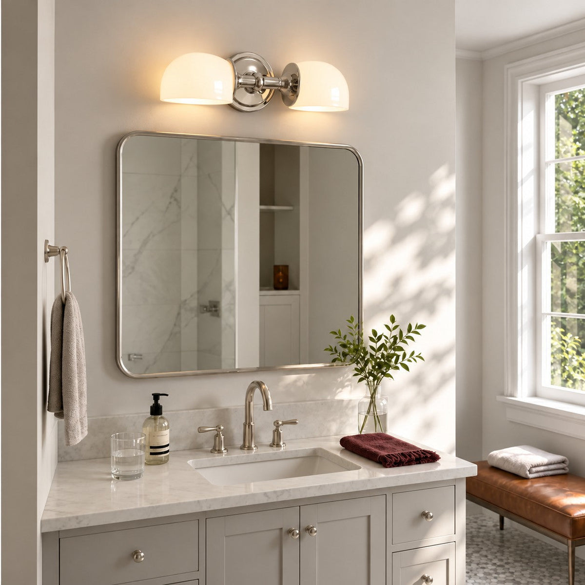 Polished nickel double milk glass sconce above a bathroom vanity mirror