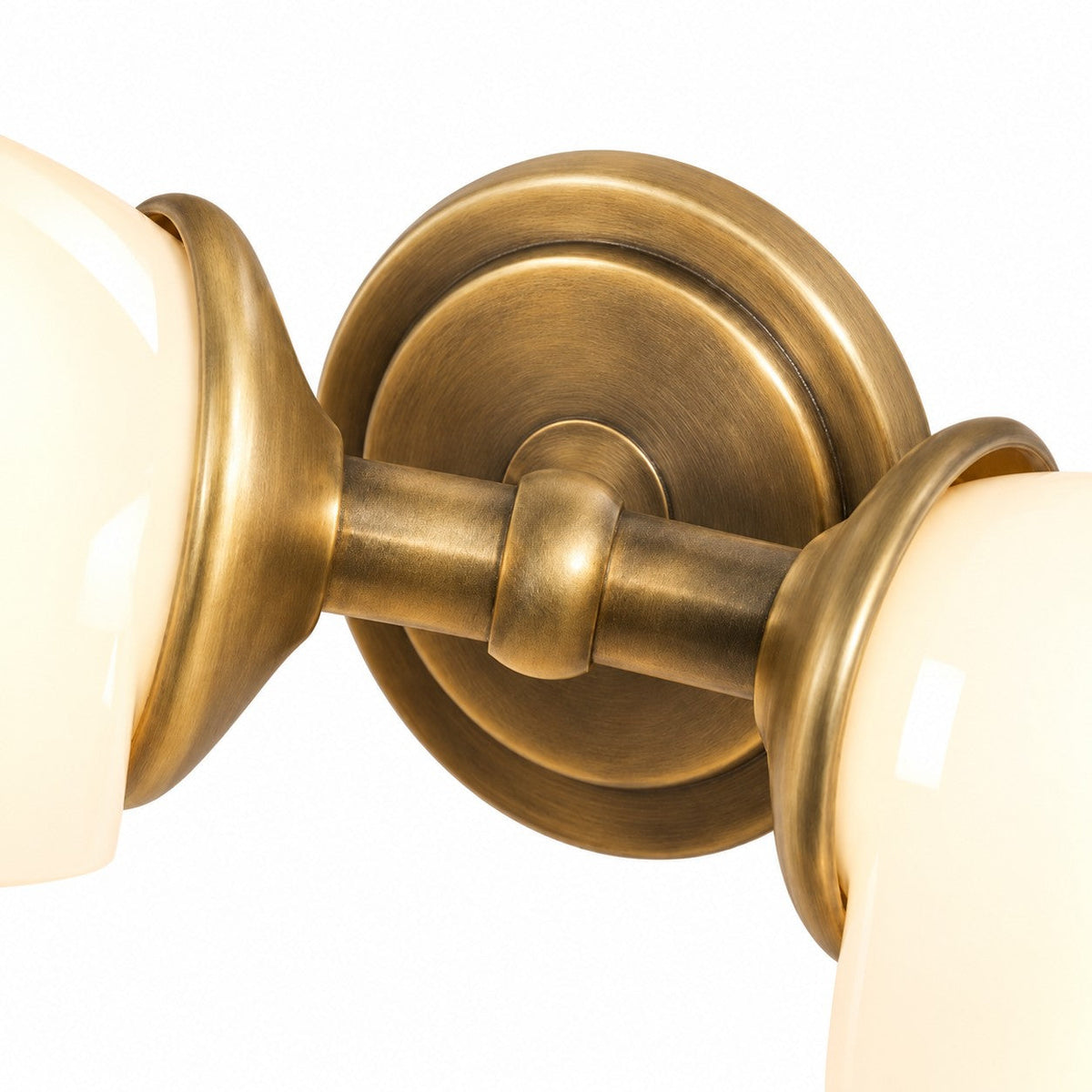 Tumbled brass backplate and arm detail of the Gemelle Opaline sconce