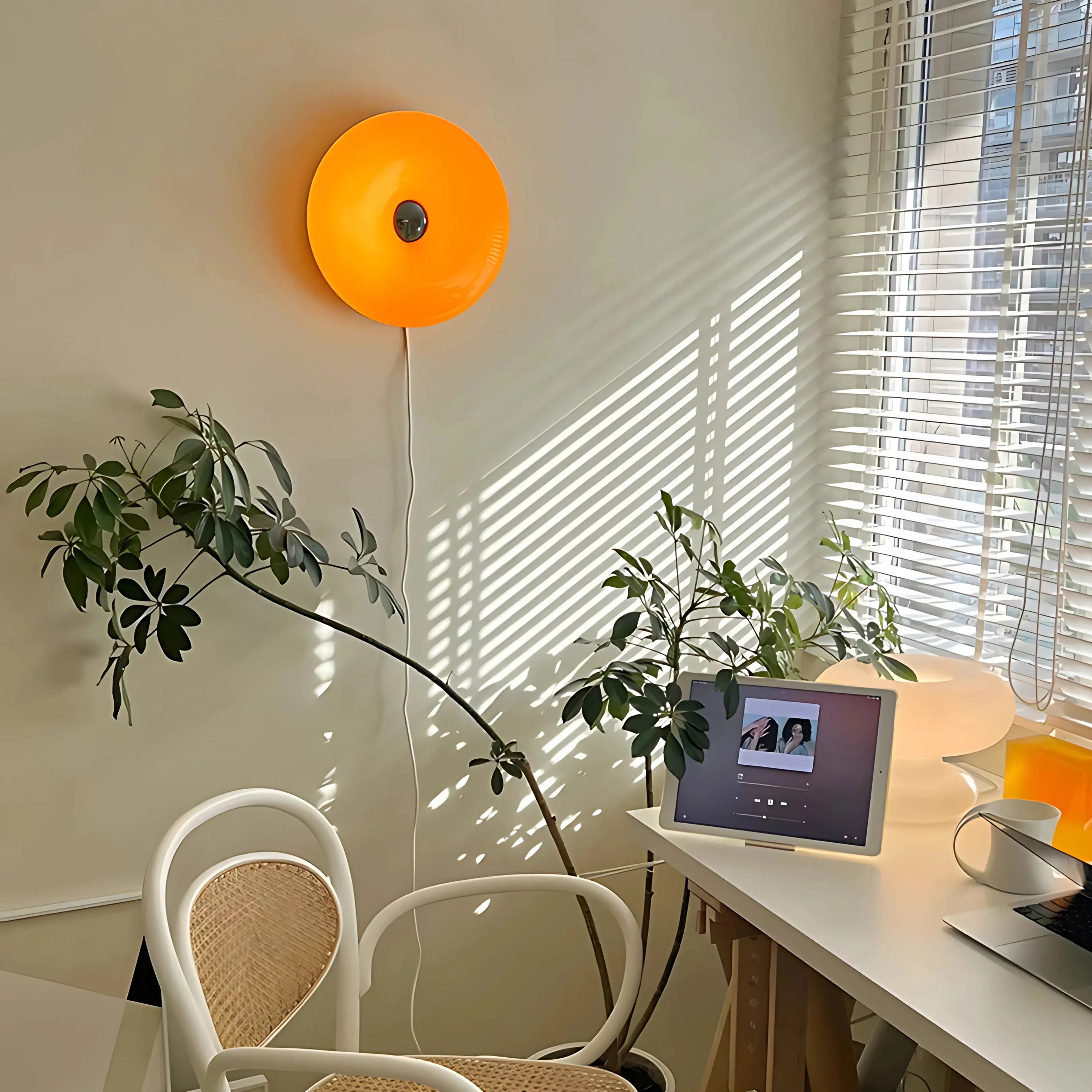Sole Ambrato amber donut lamp wall-mounted beside a plant
