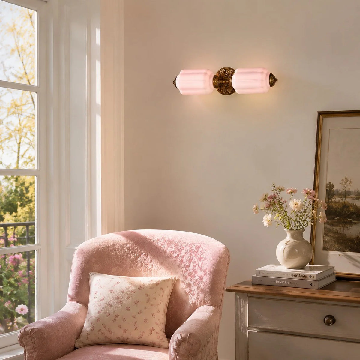 Raggiera Deco wall light with pink glass and brass plate above a blush armchair by a window