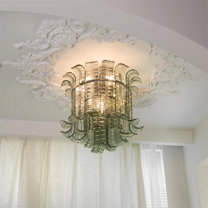 Sage green Murano-style glass flush mount lit warm on a decorative ceiling