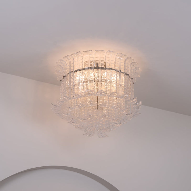 Clear Murano-style glass flush mount ceiling light lit in a bright room with an arched doorway