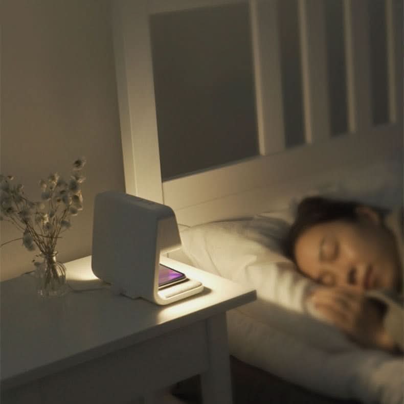 Aurora night light glowing softly on a nightstand beside someone sleeping