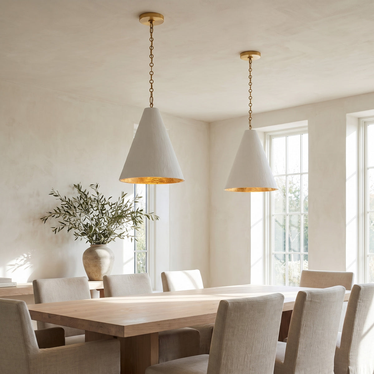 Pair of Calma Gessata plaster cone pendants with gold-leaf interiors over a pale oak dining table