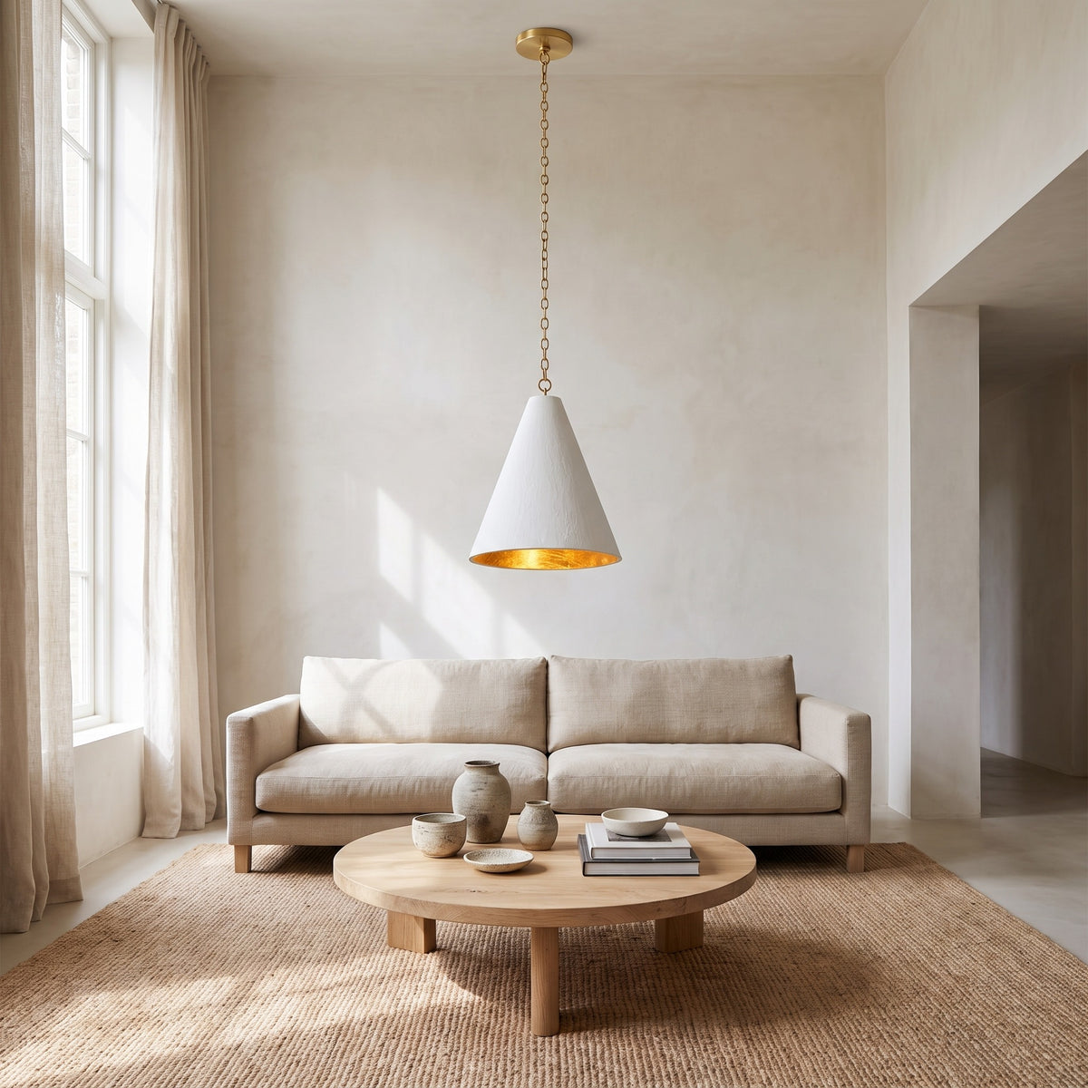 Calma Gessata plaster cone pendant on a long brass chain above a coffee table in a wabi-sabi living room