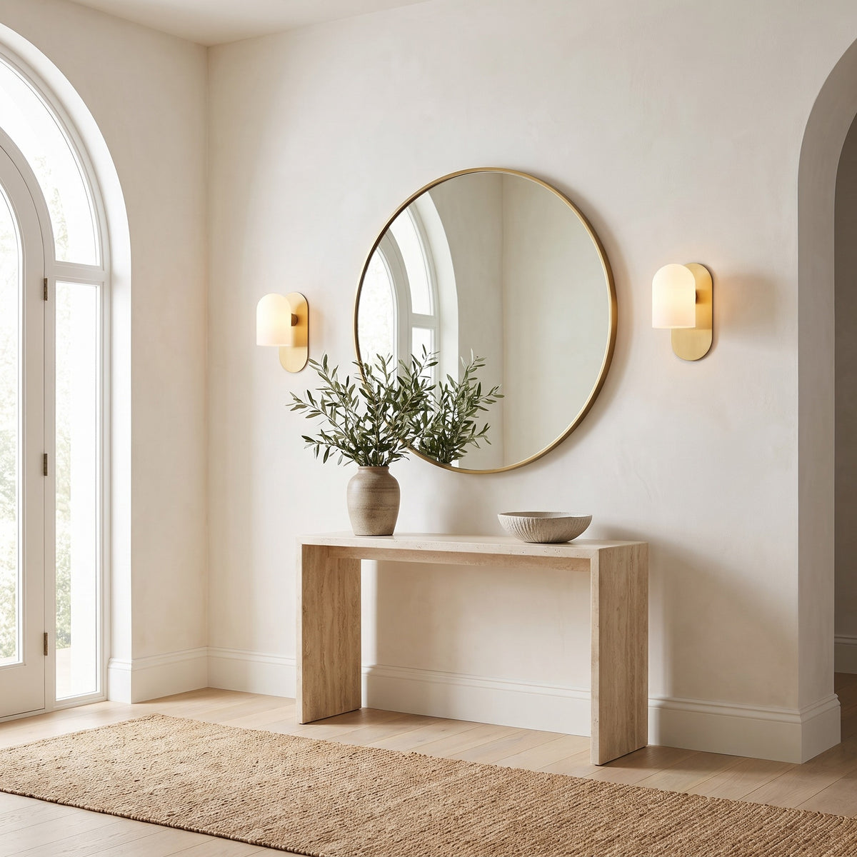 Pair of Capsula Opalina brass wall sconces either side of a round mirror in an entryway