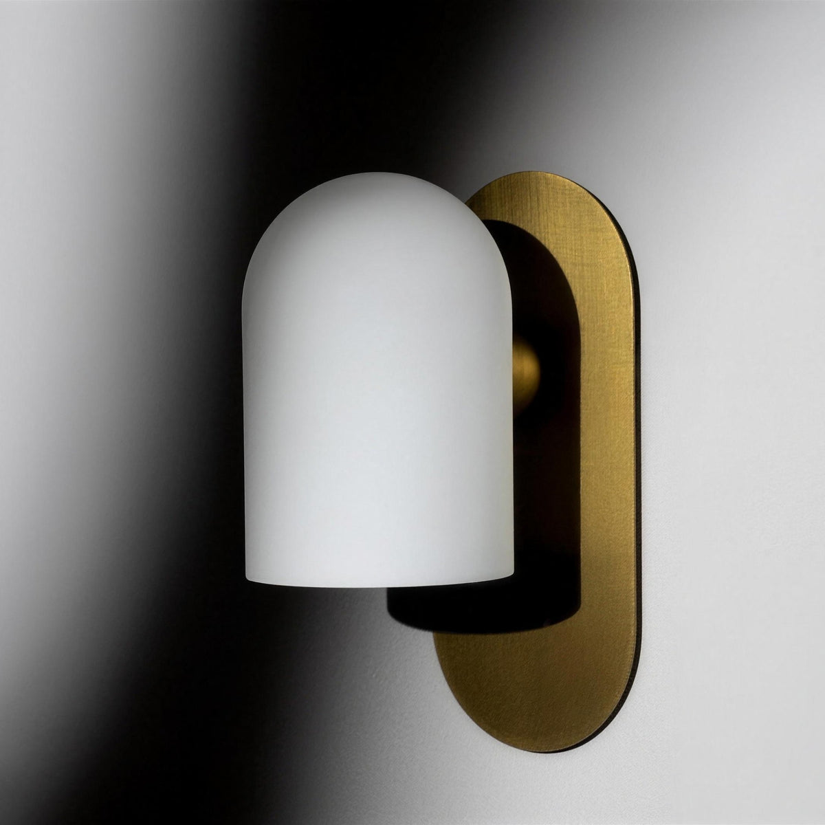 Capsula Opalina brass wall sconce in soft light and shadow