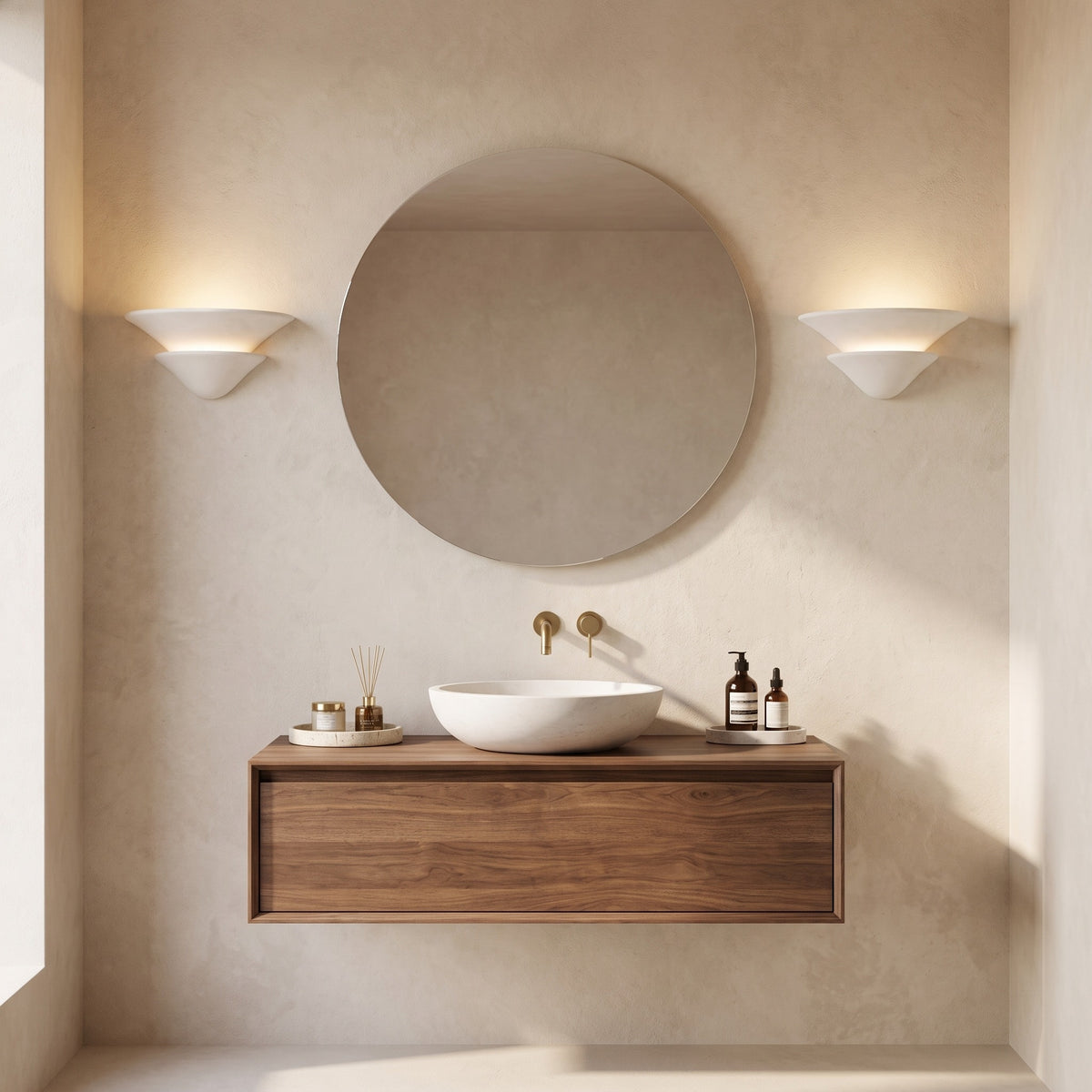 Pair of Coppa Serena alabaster wall sconces either side of a round mirror above a walnut vanity