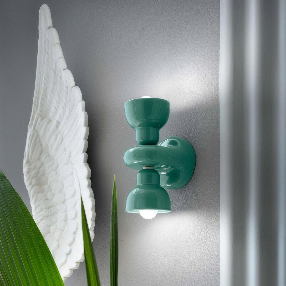 Turquoise ceramic up down wall sconce on a soft grey wall