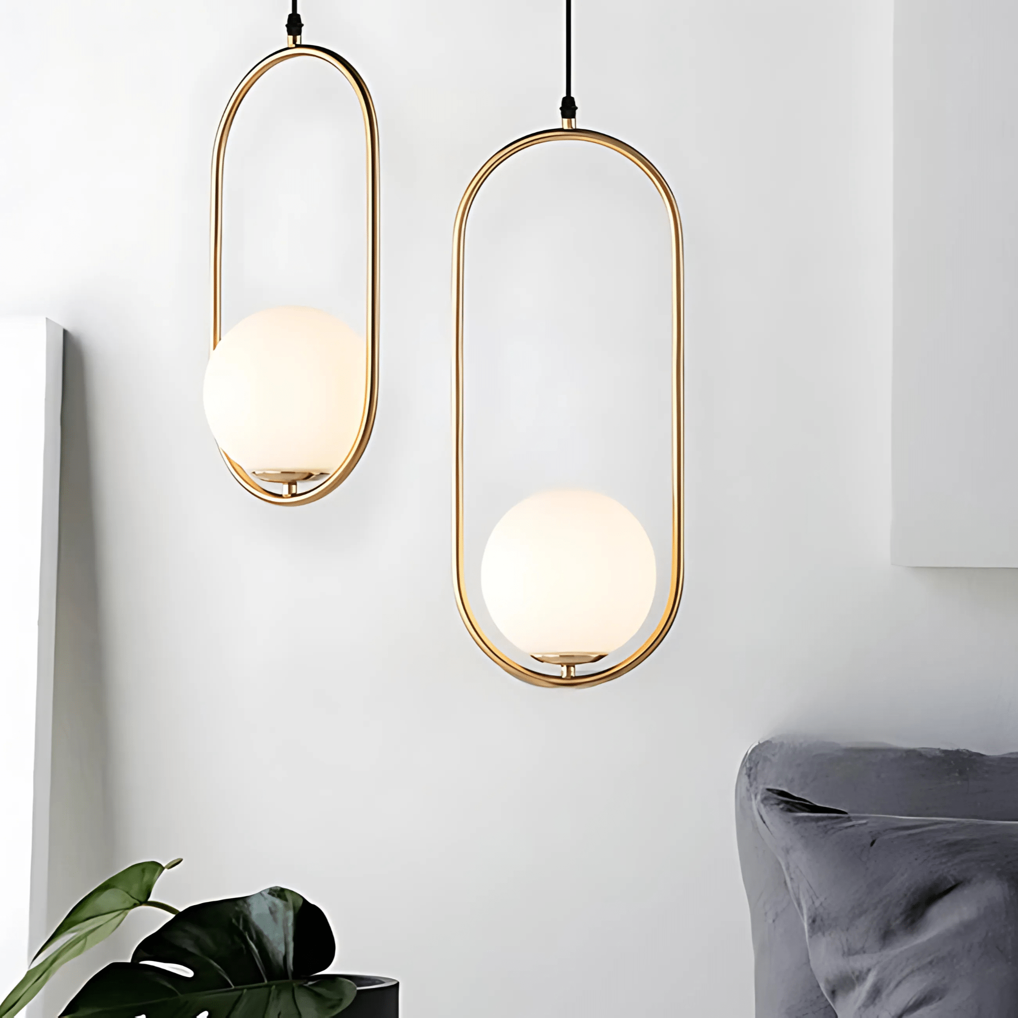 Two gold Sfera oval glass-globe pendants on a soft white wall