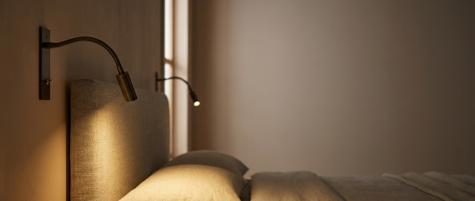 Penombra adjustable bronze wall reading light in a warm bedroom, widescreen banner
