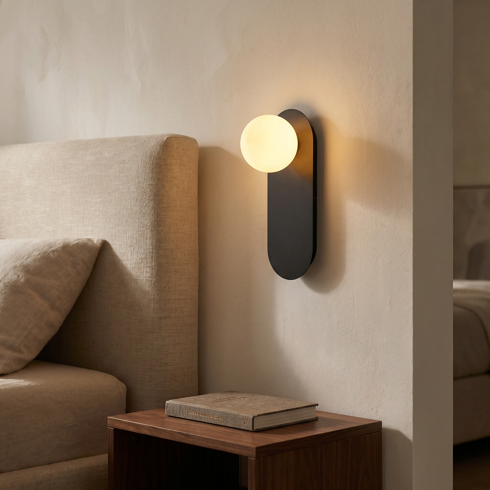 Black Sfera Lucente wall sconce with warm 3000K glow in a cozy bedroom