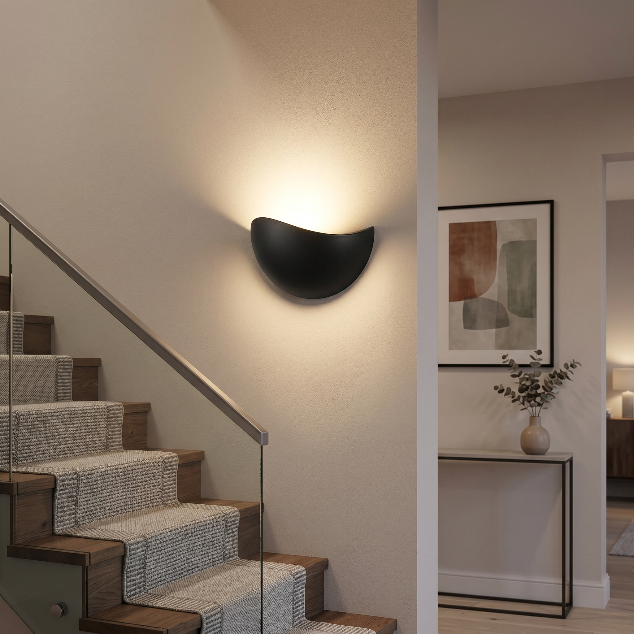 Black half-moon wall sconce in a hallway beside a staircase