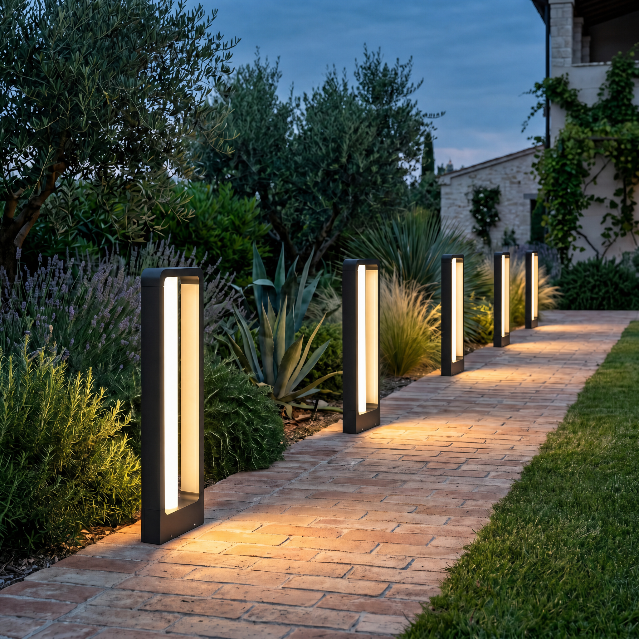 Row of black bollard path lights glowing warm along a brick garden walkway at dusk