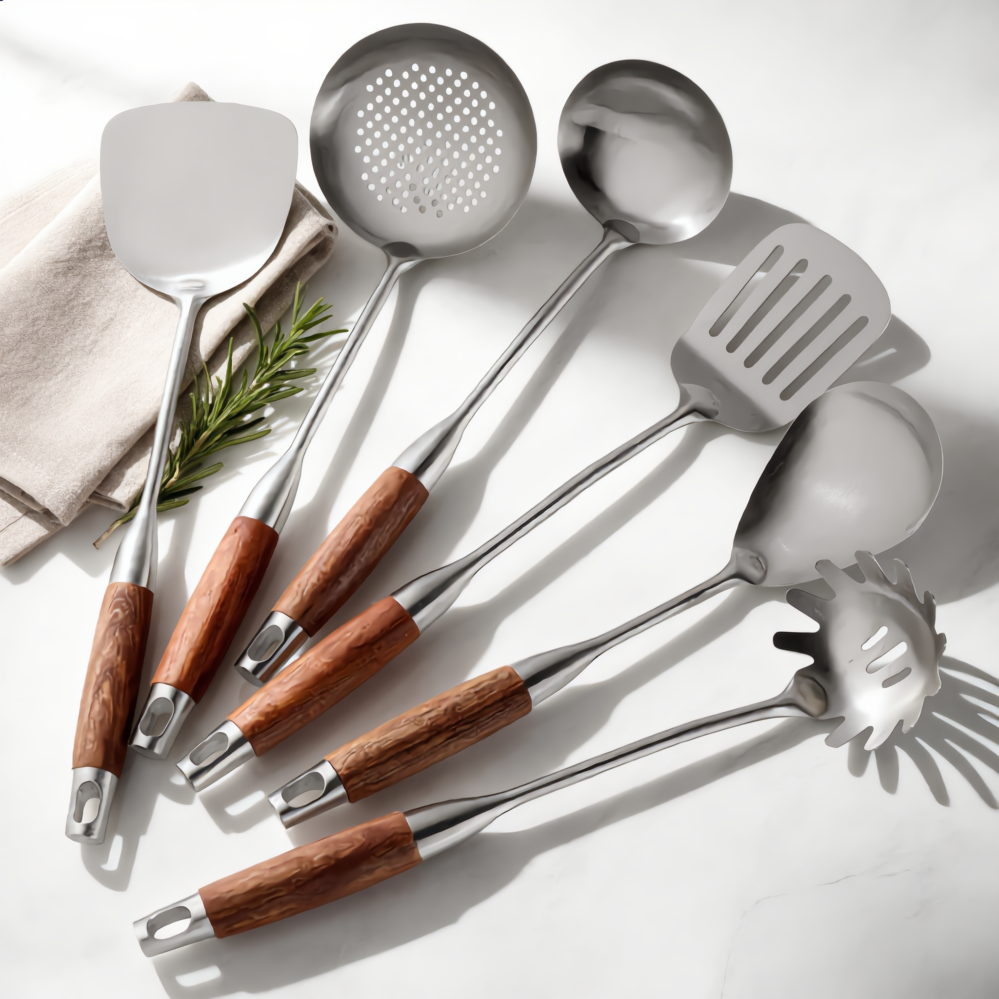 The six steel utensils with rosewood handles styled on marble with rosemary
