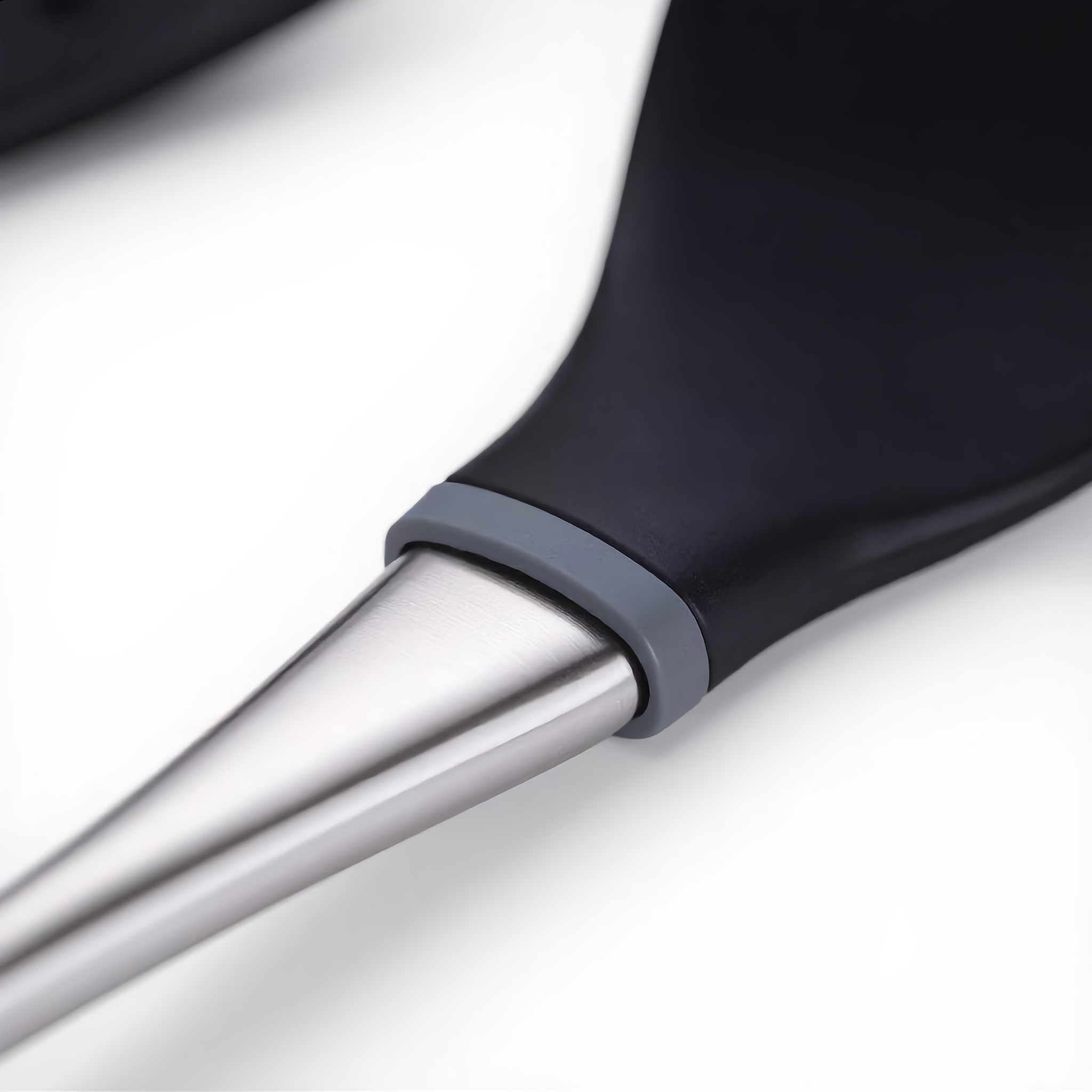 Macro of the black silicone head meeting the brushed silver steel handle on a Lustro utensil