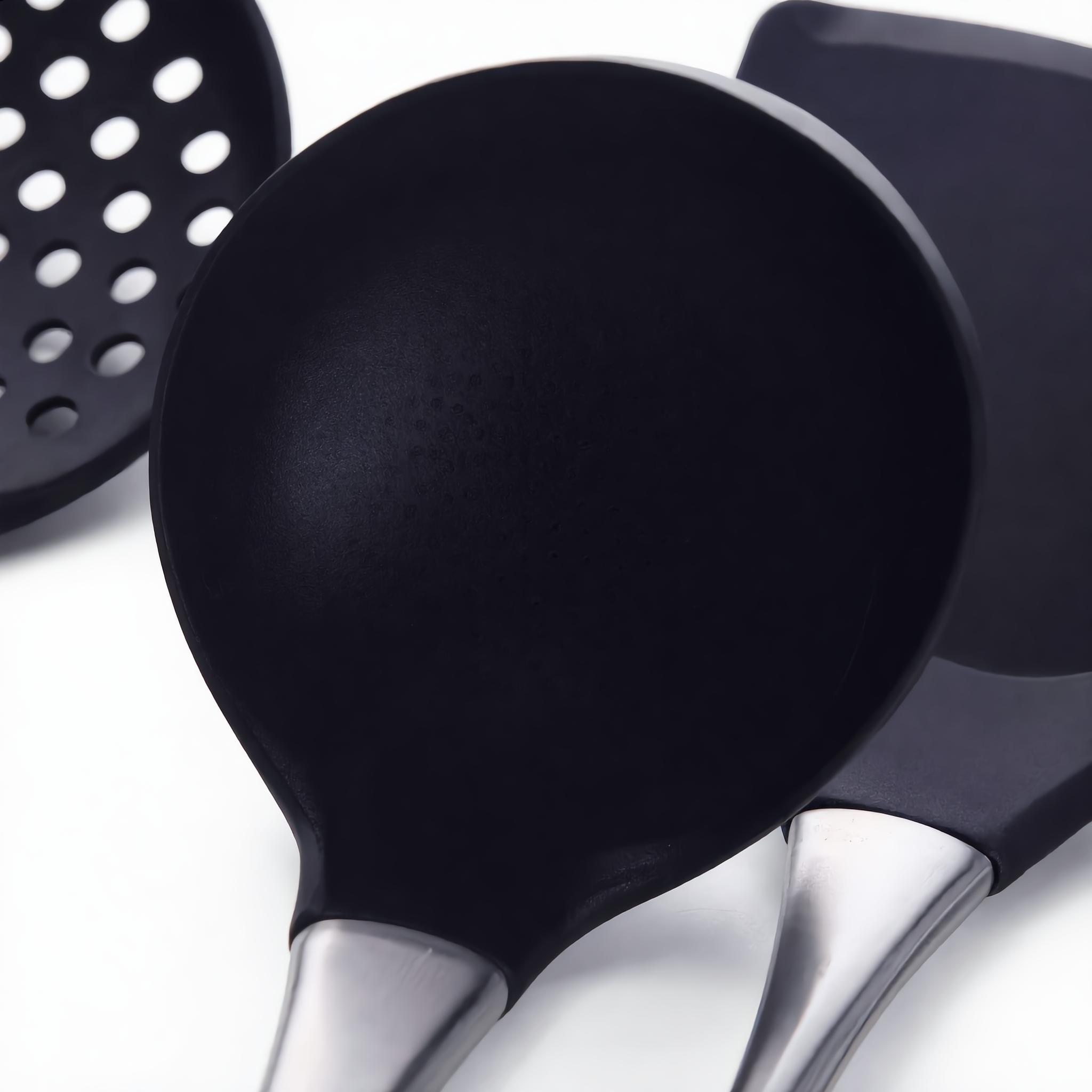 Macro of the black silicone slotted skimmer, ladle and turner heads on the Lustro set