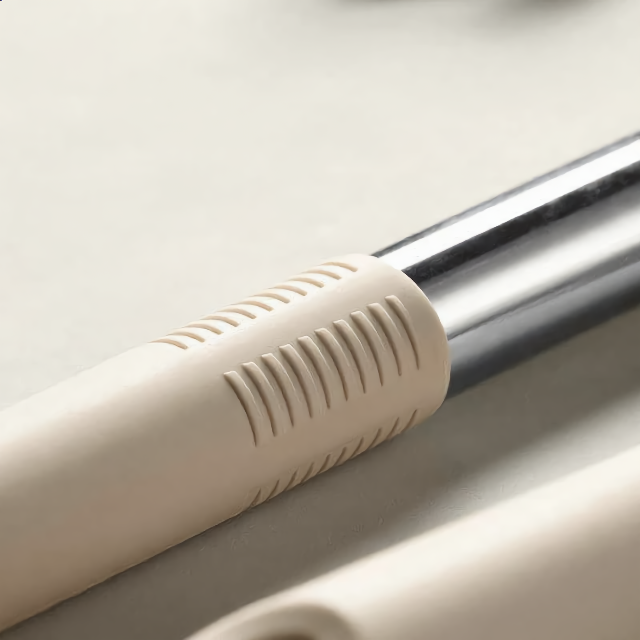 Macro of the ribbed cream silicone grip meeting the stainless steel handle