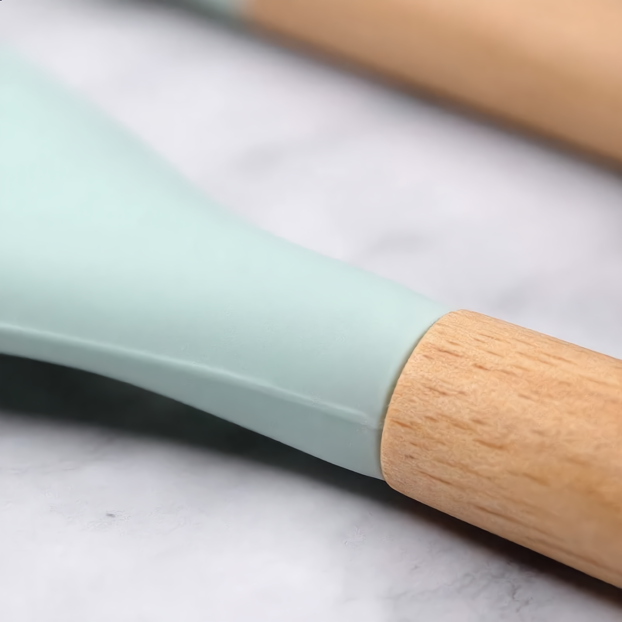 Macro of a silicone head meeting its natural wood handle