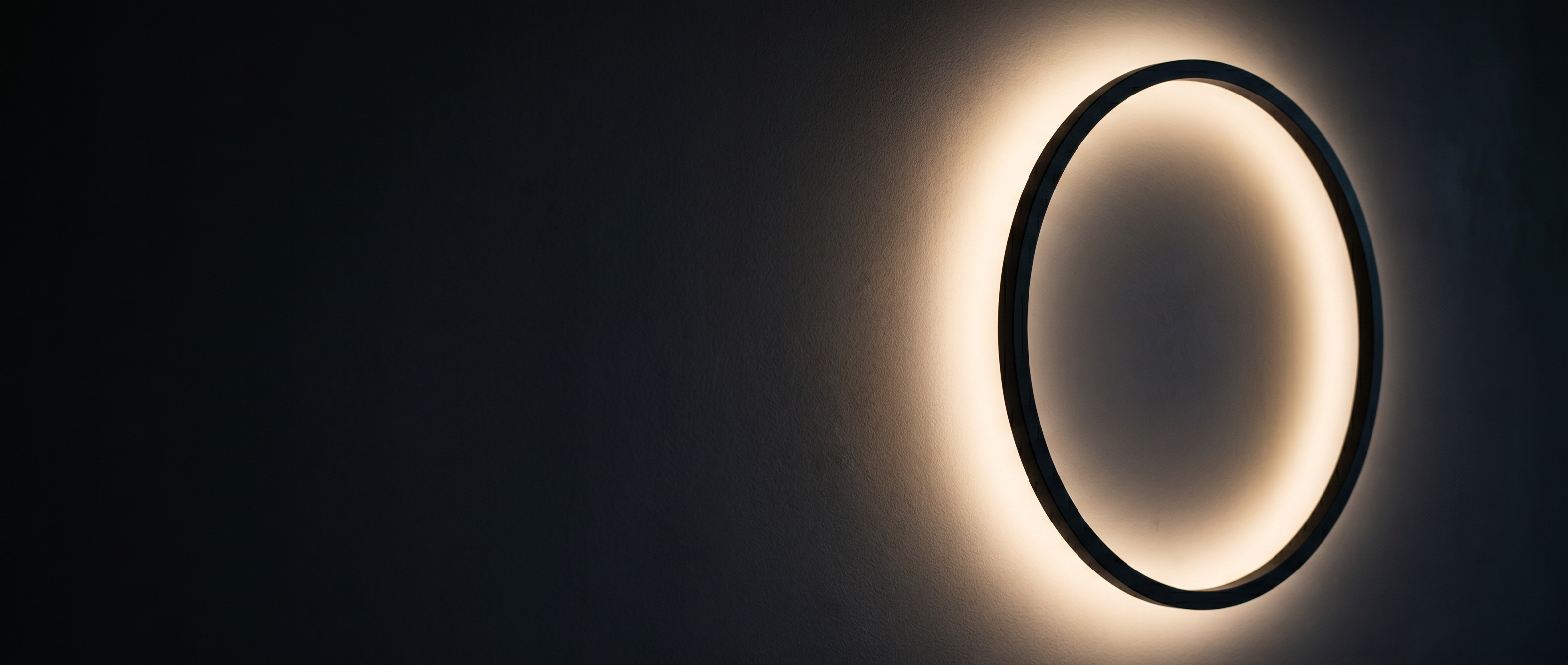 Eclisse Halo Ring Wall Light glowing warm on a dark wall