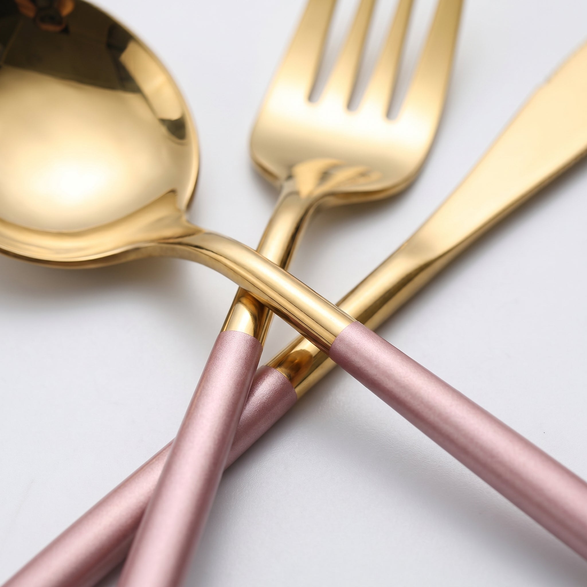 Macro detail of polished gold head and pink handle two-tone flatware