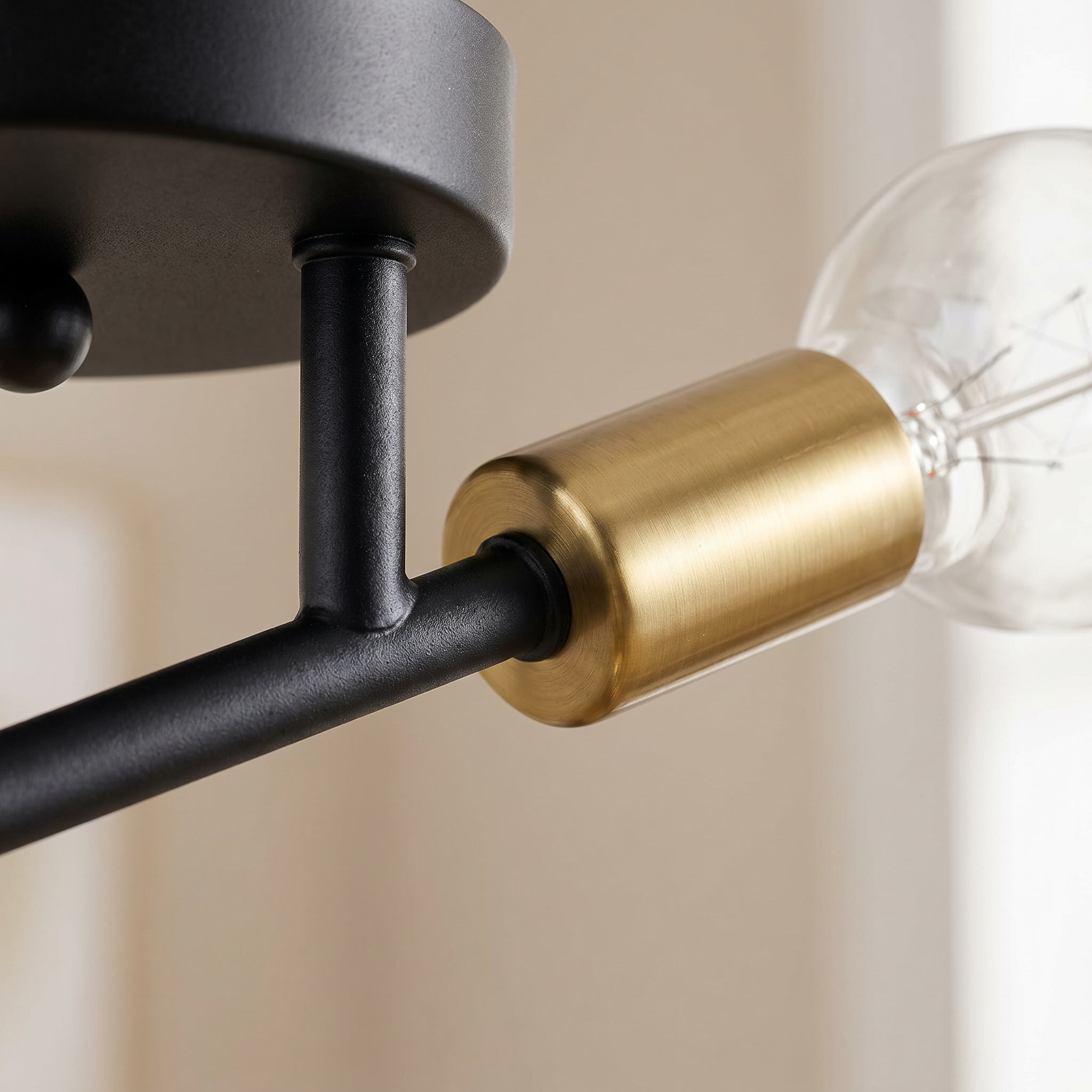 Macro detail of the black arm and brushed brass bulb socket