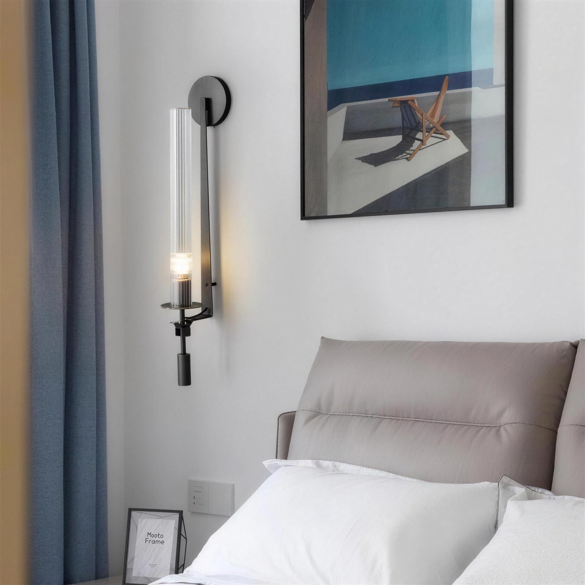 Black ribbed glass wall sconce in a bedroom beneath framed art