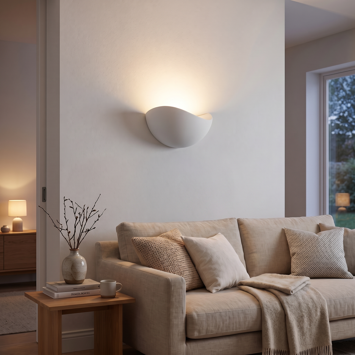 White Mezzaluna sconce glowing upward above a sofa in a cosy living room
