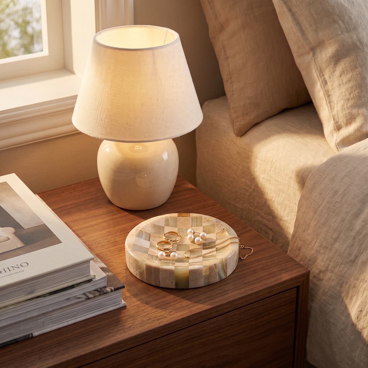 Olvera trinket dish holding gold rings and pearl earrings on a walnut nightstand