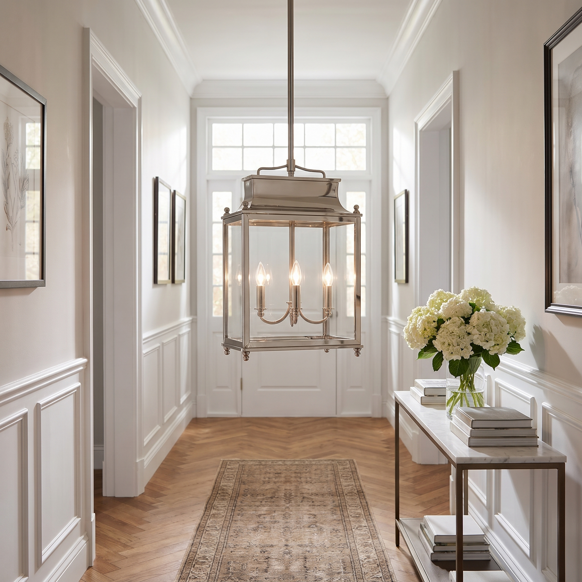 Polished nickel glass lantern pendant in a paneled entrance hallway with hydrangeas on a marble console