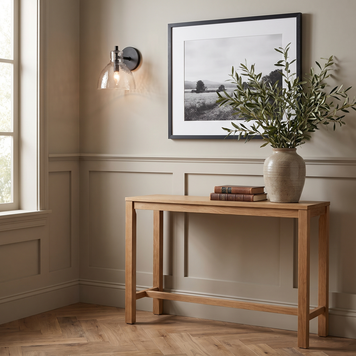 Black hammered glass wall sconce beside a framed photograph above an oak console in an entryway