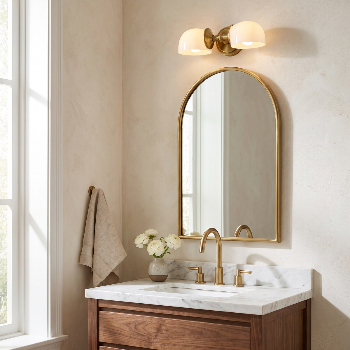 Tumbled brass double milk glass sconce above an arched mirror in a powder room