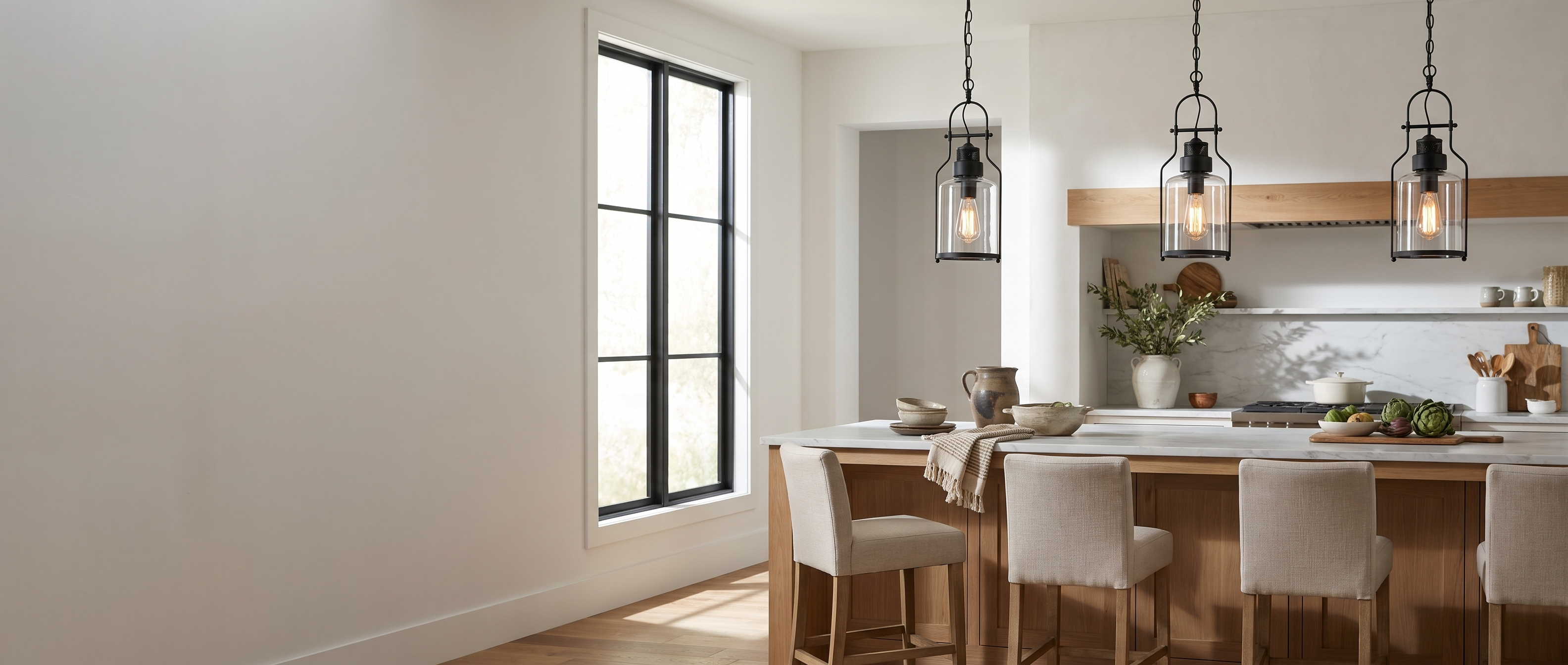 Three black glass jar pendants over a white oak kitchen island