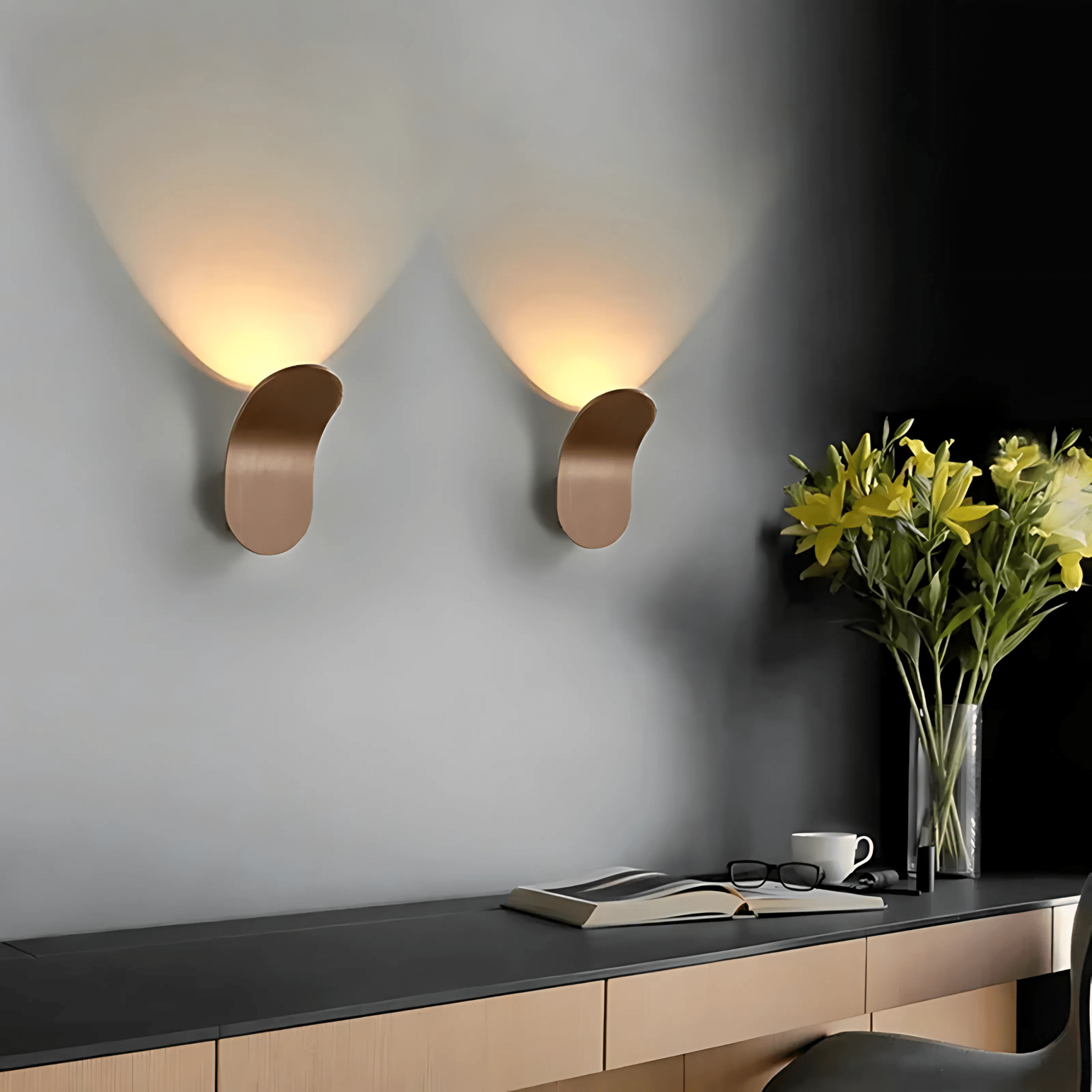 Coffee bronze curved wall sconces over a desk styled with flowers