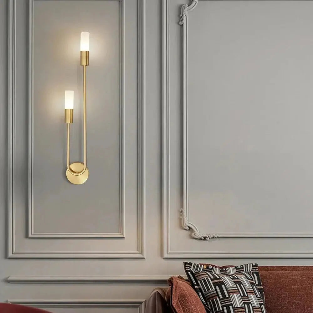 Gold curved wall sconce on a panelled wall above a sofa
