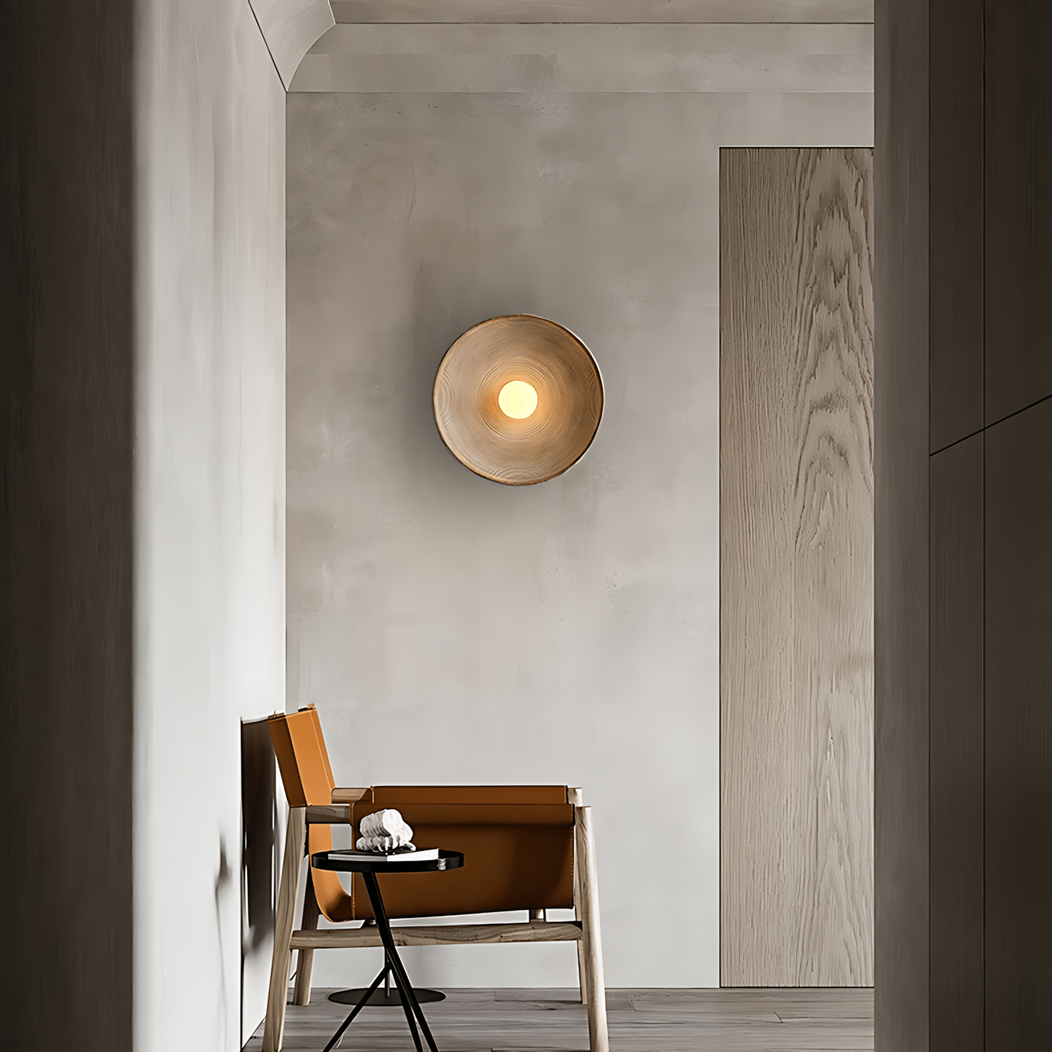 Aurelia Sculptural Wall Sconce glowing warmly above a tan leather armchair