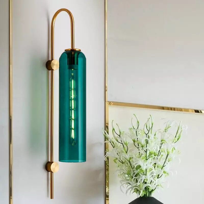 Aqua green glass wall light with brass arm beside a gold mirror