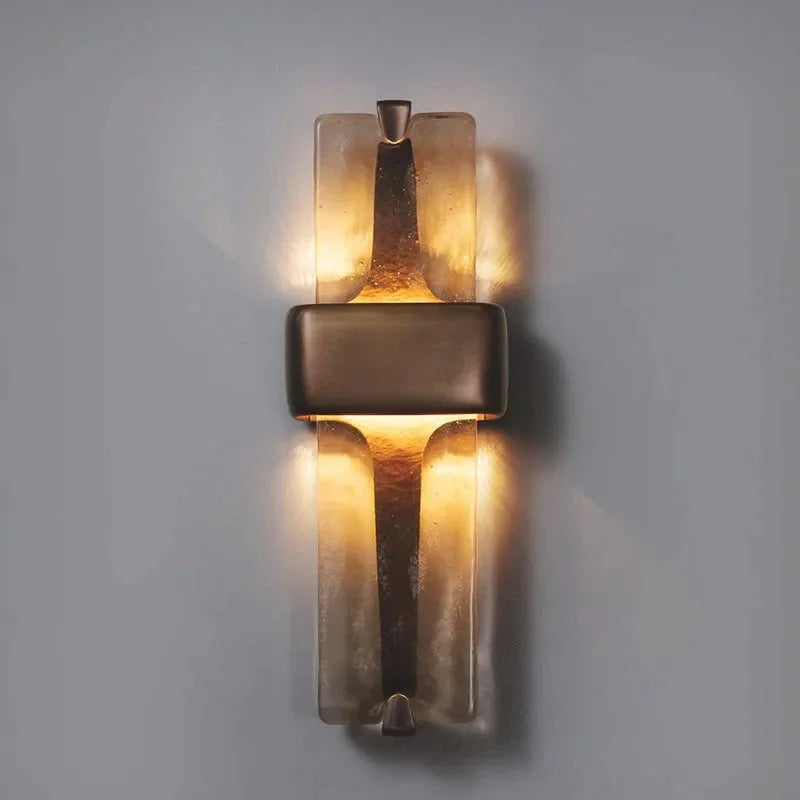 Vetro Colato textured glass and brass wall sconce glowing warm white on a grey wall