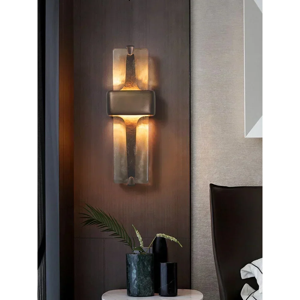 Vetro Colato textured glass wall sconce glowing beside a bed on a dark wood panelled wall