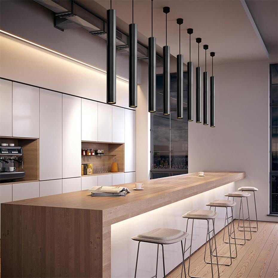 Row of black Flauto tube pendants over a kitchen bar in a modern loft