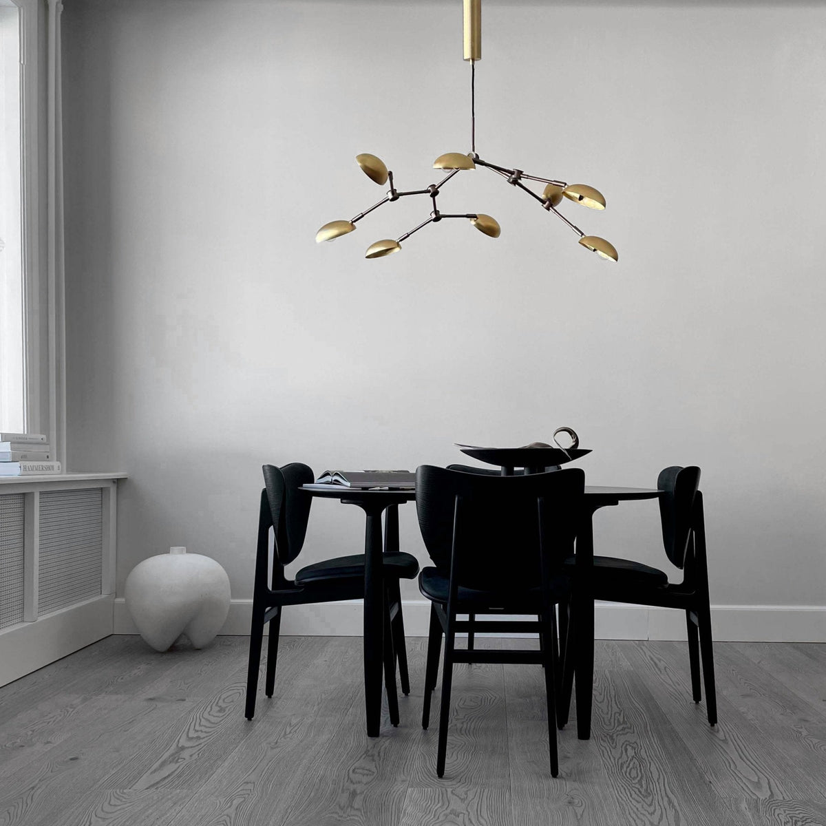 Ramo Goccia brass branch chandelier above a round dining table in a calm grey dining room