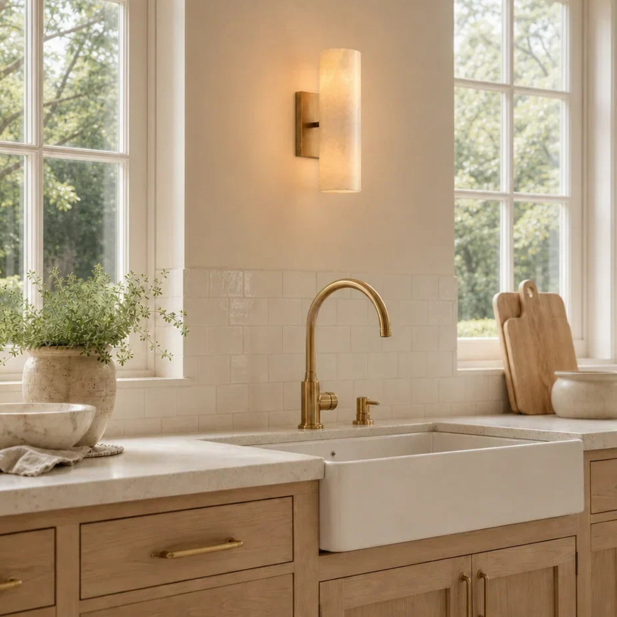 Brass alabaster tube sconce above a farmhouse kitchen sink