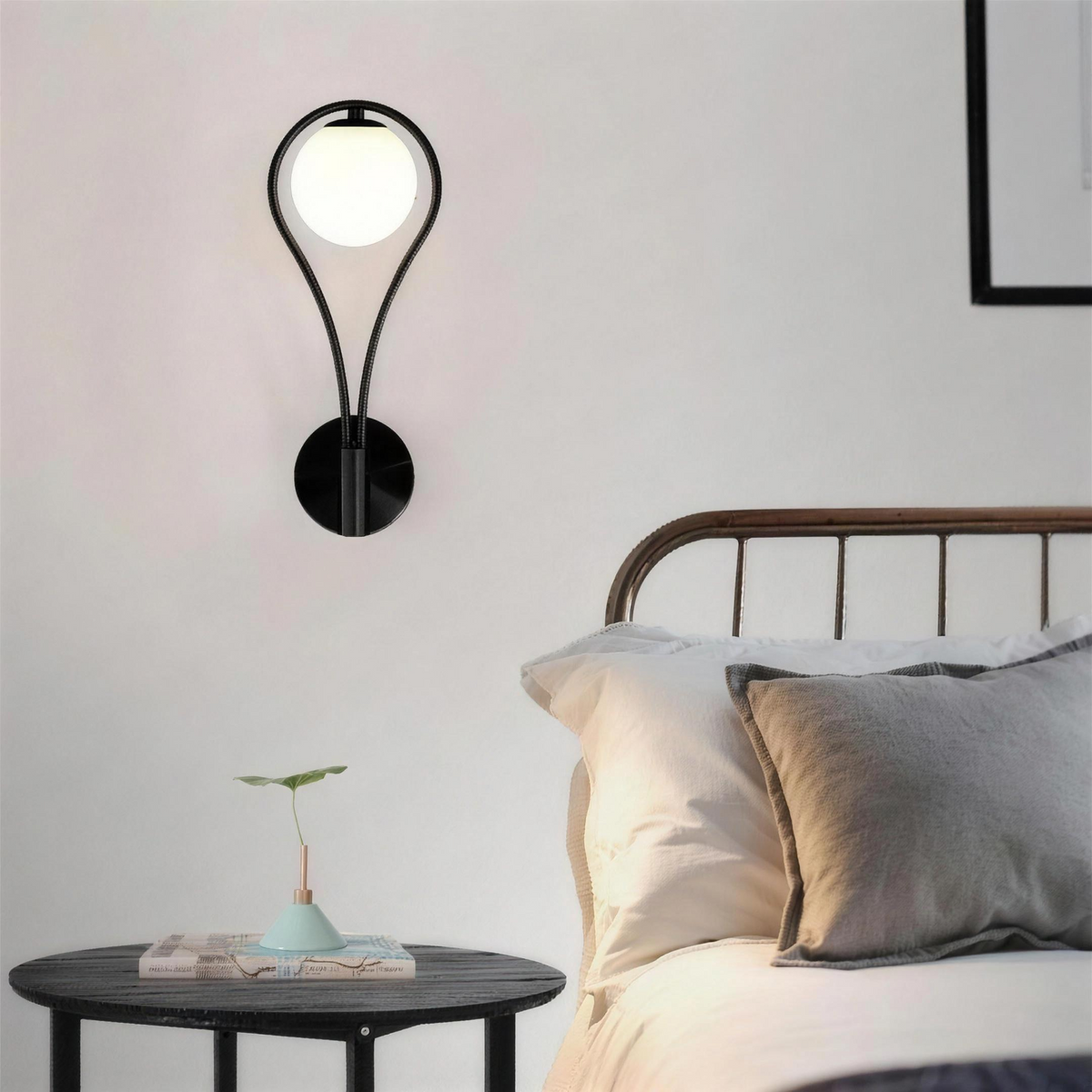 Black globe wall sconce above a bedside table in a modern bedroom