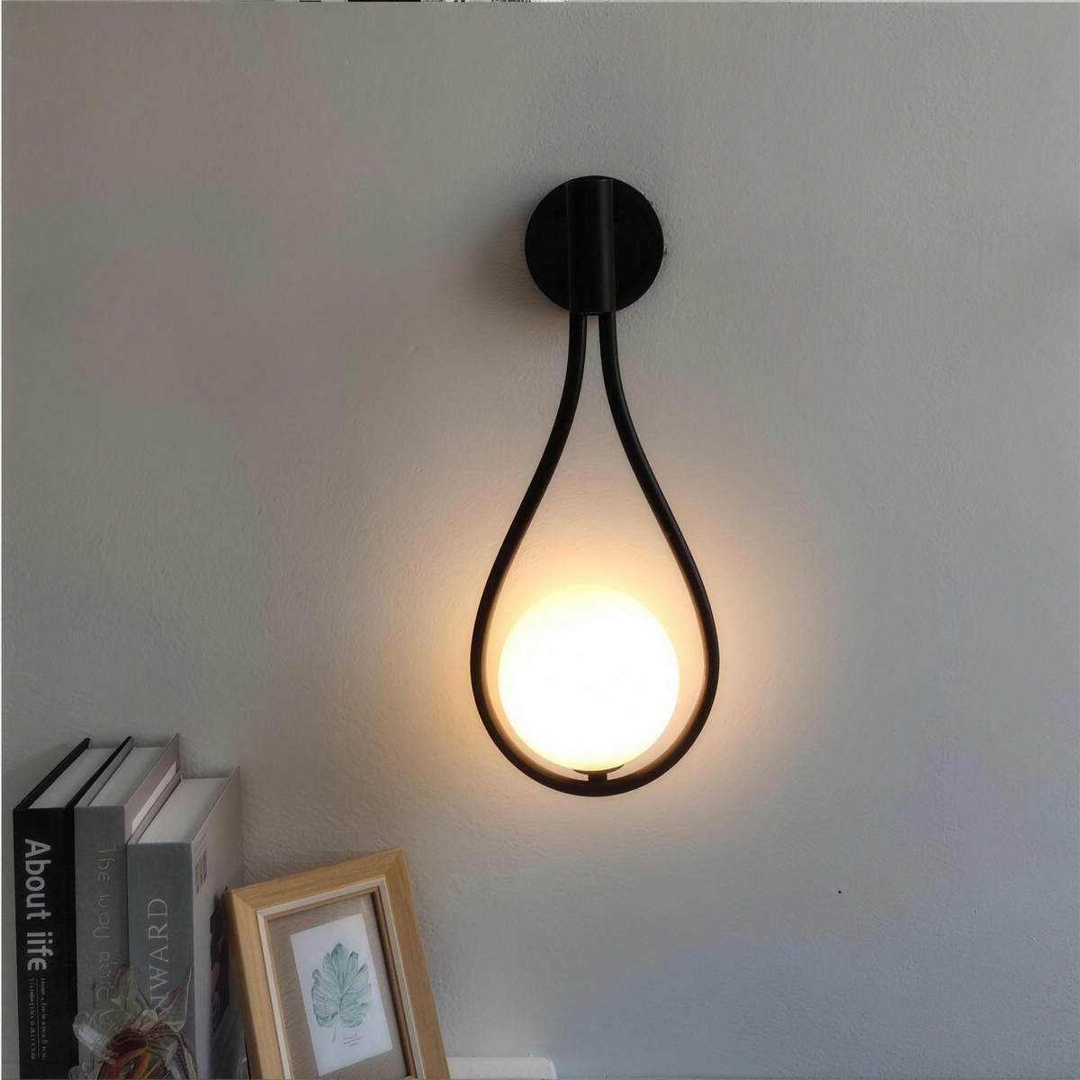 Black opal globe wall sconce glowing above a shelf of books