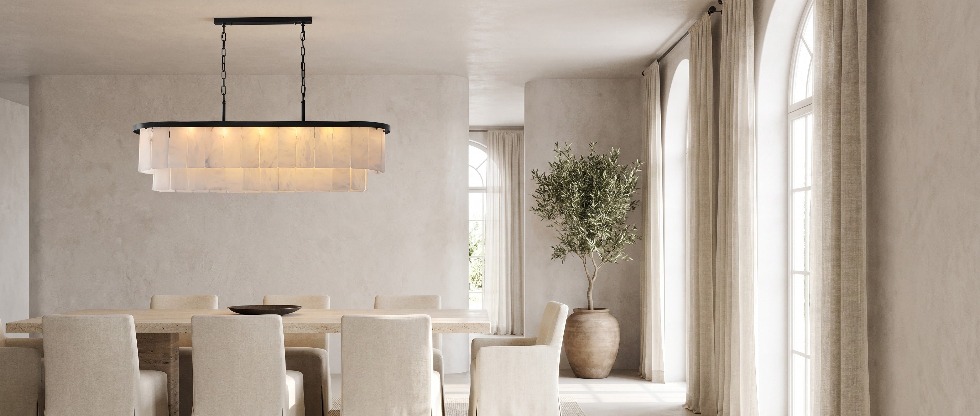 Velo Alabastro alabaster linear chandelier over a travertine dining table in a bright dining room