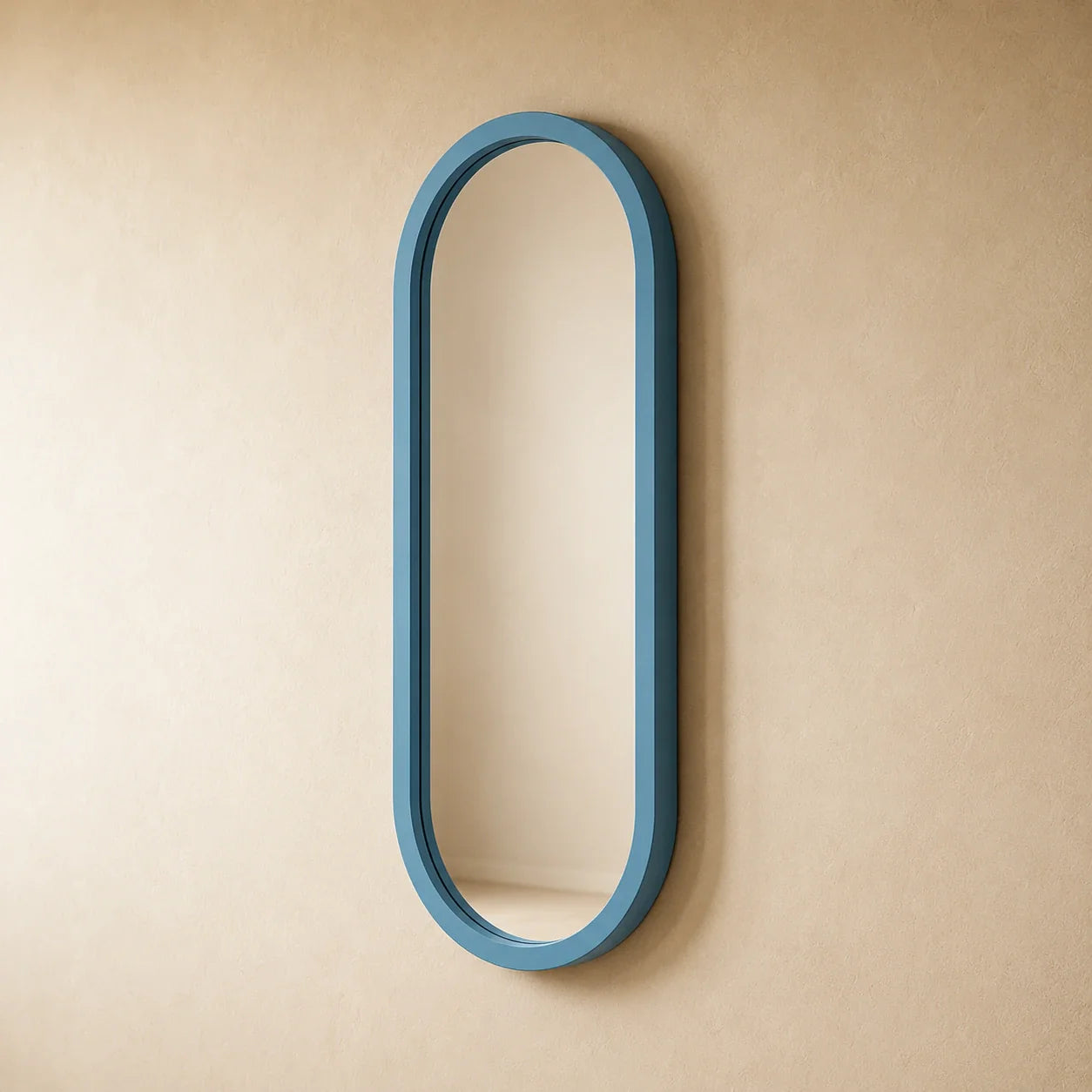 Dusty-blue capsule wall mirror at an angle in a styled interior